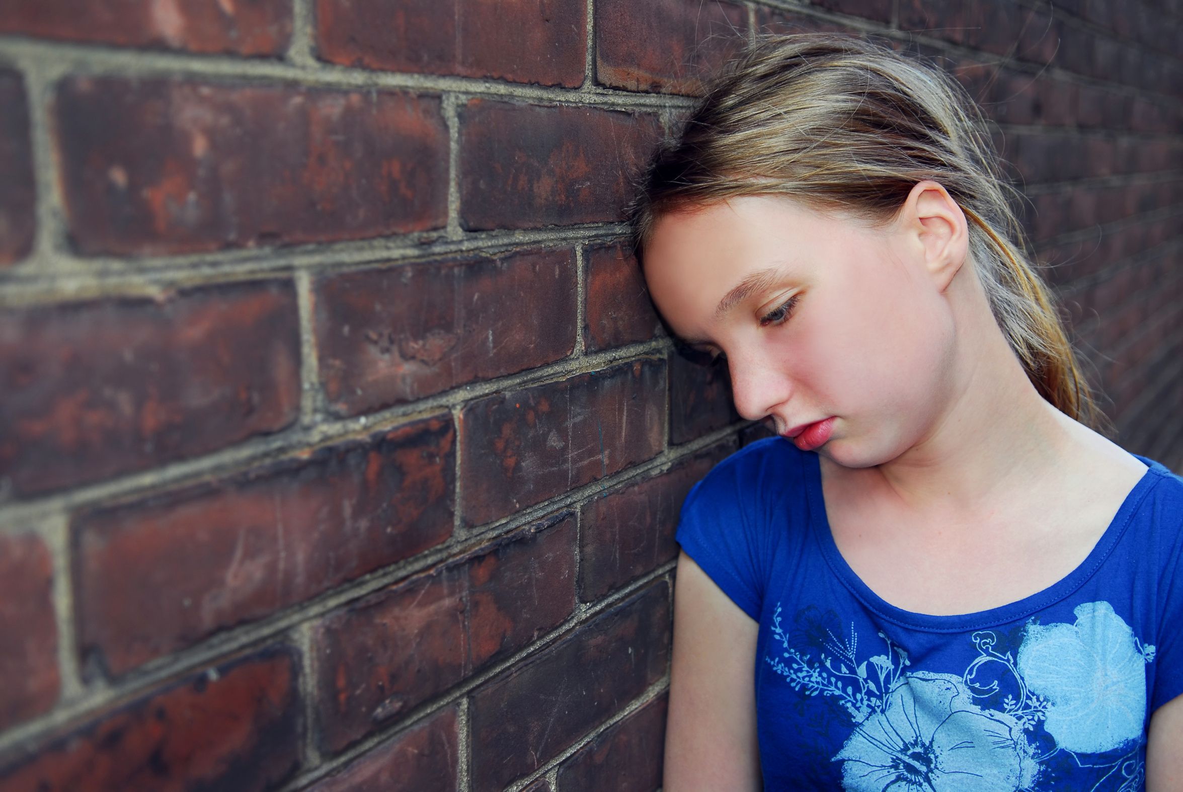 Young girl near brick wall looking upset